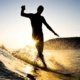 surfer at sunset cruising down a wave