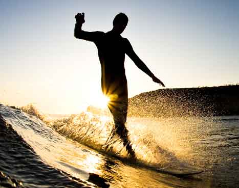 surfer at sunset cruising down a wave