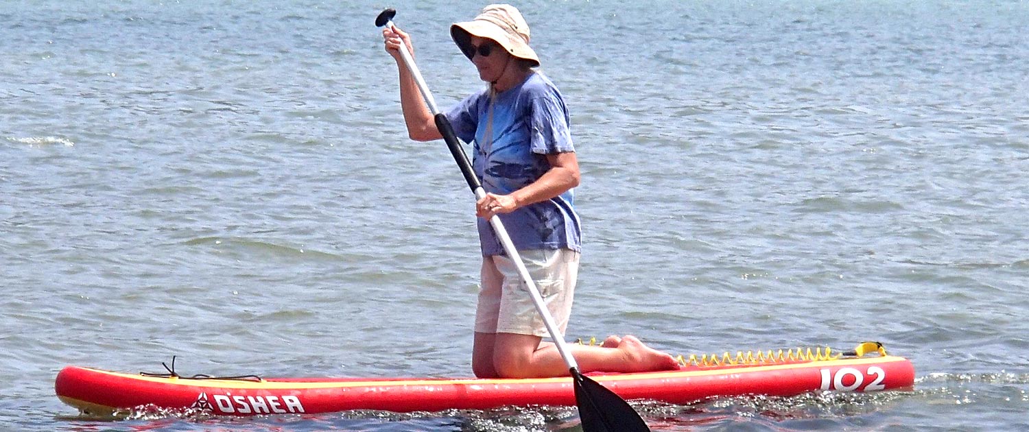 Elderly woman stand up paddle boarding SUP SUPing after using CoolBoard balance board