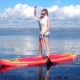 Lady on her Stand Up Paddle Board using her balance training to balance on her SUP on the sea