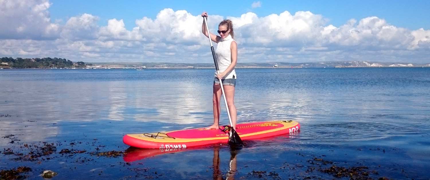 Lady on her Stand Up Paddle Board using her balance training to balance on her SUP on the sea