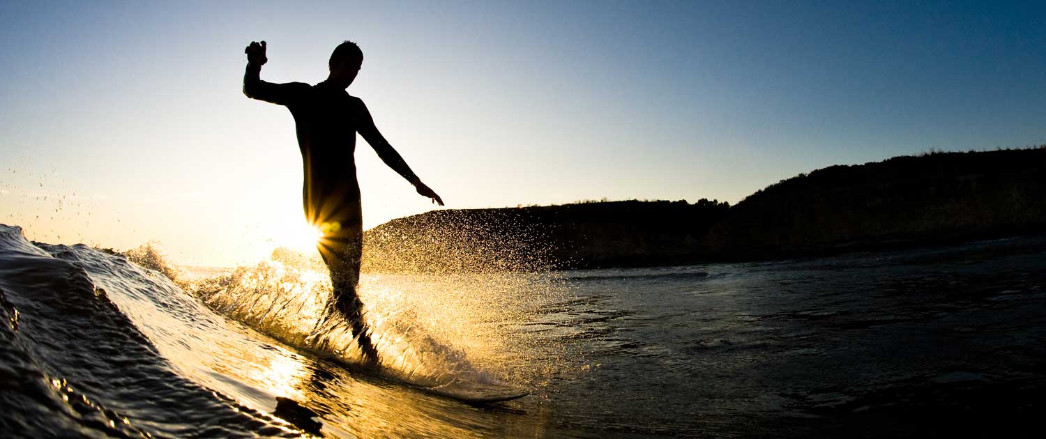 surfer using his balance training to surf a wave at sunset