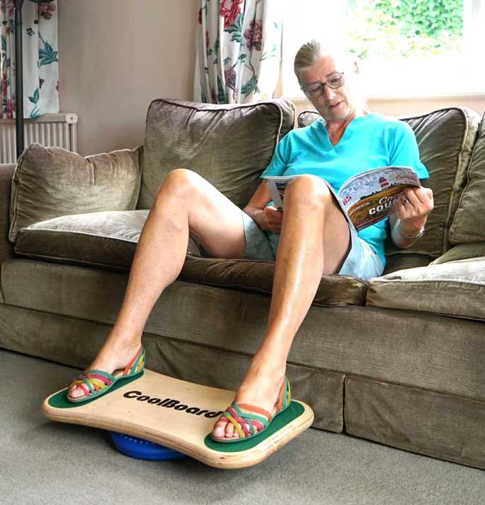 elderly lady using CoolBoard wobble board sat on a sofa while reading a magazine