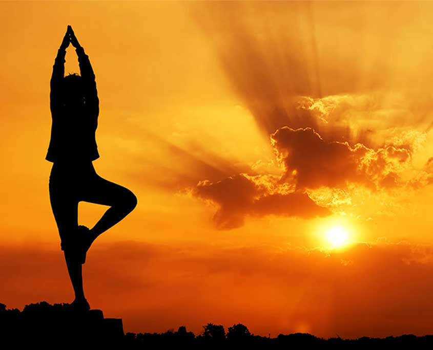 calming image of lady in yoga tree pose at sunset